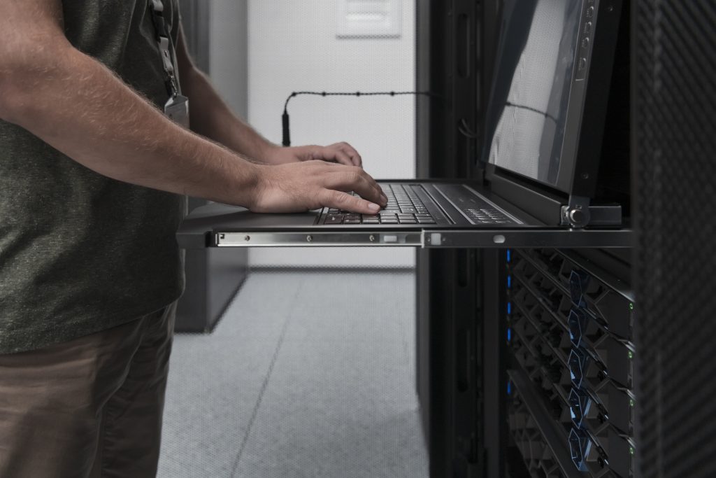 Close up on Data Center Engineer hands Using keyboard on a supercomputer Server Room Specialist Facility with Male System Administrator Working with Data Protection Network for Cyber Security.
